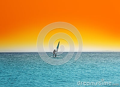 Surfer on blue sea under orange sky Stock Photo