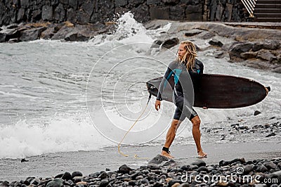Surfer with a board in hands on the beach Stock Photo