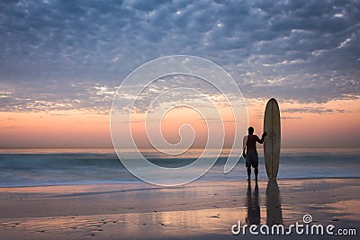 Longboard surfer silhouette at golden sunset Stock Photo