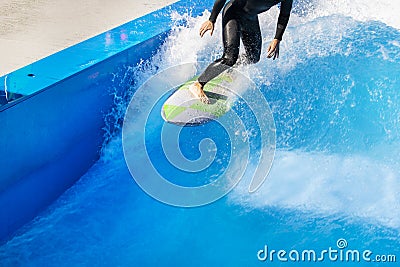 A surfer enjoying the crests of the waves in an urban wave pool in his black wetsuit Stock Photo