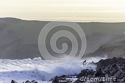 Surfer getting out of the water after evening surf in rough sea Editorial Stock Photo