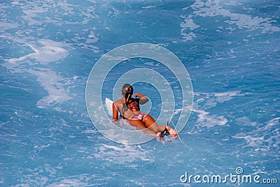 Surfer girl paddling to catch a wave Stock Photo