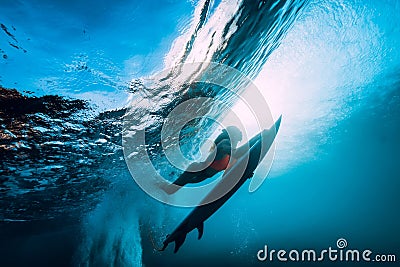 Surfer girl with surfboard dive underwater with fun under big ocean wave. Stock Photo