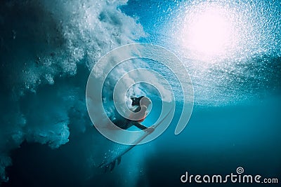 Surfer girl with surfboard dive underwater with under big ocean wave. Stock Photo