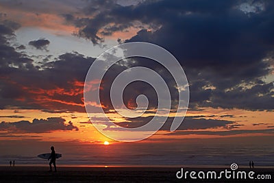 Surfer on the ocean beach at sunset or sunrise Stock Photo