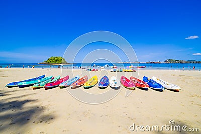 Surfer on Pretty beach and ocean with sailboat Stock Photo