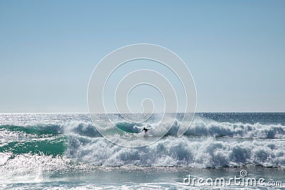 Surfer riding a surfboard on a large set of waves in an ocean Stock Photo