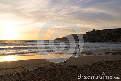 Surfer on the seashore on the beach in Melieha. Sunset in Golden Bay Malta Stock Photo