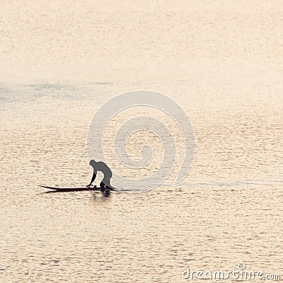 A surfer pushing his surfboard at sunset Stock Photo