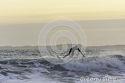 Surfer touching the wave while catching balance during evening surf in rough sea Editorial Stock Photo