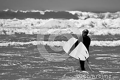 Surfer walking towards the water`s edge at Llangennith Beach on the Gower Peninsula Editorial Stock Photo