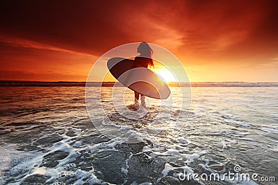 Surfer woman on beach at sunset Stock Photo
