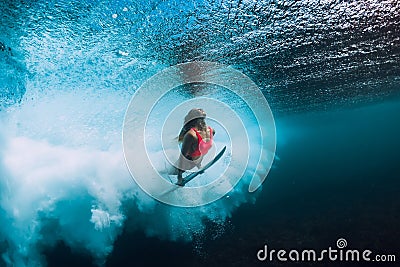 Surfer woman with surfboard dive underwater with under ocean wave. Stock Photo