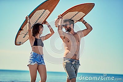 Surfers at the beach- Young couple of surfers walking on the beach and having fun in summer Vacation. Extreme Sport. Stock Photo