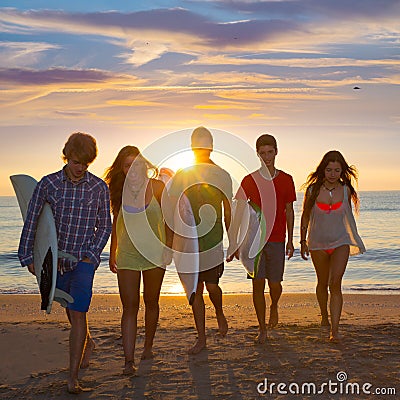 Surfers boys and girls group walking on beach Stock Photo