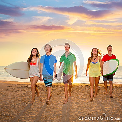 Surfers boys and girls group walking on beach Stock Photo