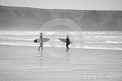 Surfers standing by the water`s edge at Llangennith Beach on the Gower Peninsula Editorial Stock Photo