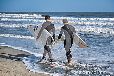 surfers walking with board on beach Charleston Editorial Stock Photo