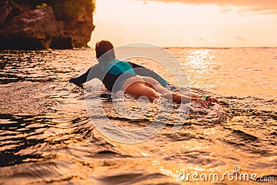 Surfgirl with perfect body on a surfboard floating in ocean. Stock Photo