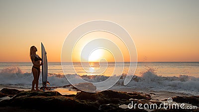 Surfing lifestyle. Silhouette of surfer girl with surfboard on the beach. Golden sunset time. Bali, Indonesia Stock Photo