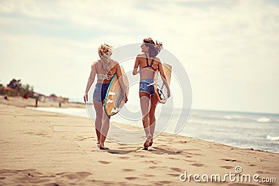 Surfing lifestyle. Surfer girls walking with board on the sandy beach Stock Photo