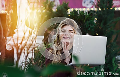 Thoughtful young woman in glasses using a computer, sitting on a bench in a city park. The concept of time is online and work in Stock Photo