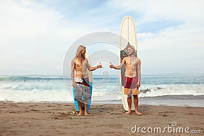 Surfing. Young Surfers Standing On Sunny Beach. Smiling Men Showing Thumb Up Near Surfboards In Sand. Stock Photo