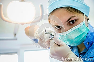 The surgeon dentist in mask holding forceps making tooth extraction Stock Photo