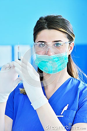 The surgeon dentist in mask holding syringe for injecting anesthesia. Stock Photo