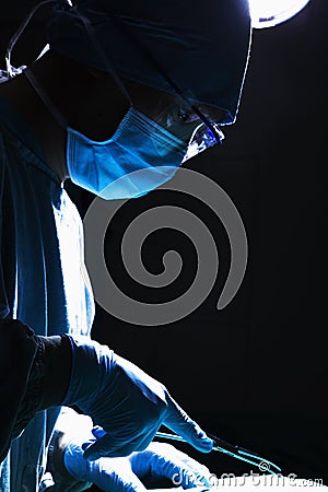 Surgeon looking down, concentrating, and holding surgical equipment in the operating room Stock Photo