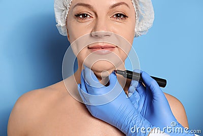 Surgeon with marker preparing woman for operation against background. Double chin removal Stock Photo