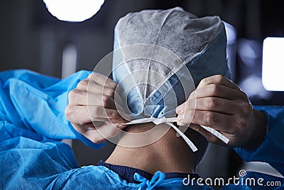 Surgeon tying surgical cap in preparation, back view Stock Photo