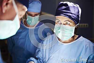 Surgeon during a very important operation in dark operating room Stock Photo