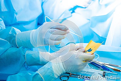 The surgeon's hand in a sterile glove holds a fibrin glue dispenser. Stock Photo