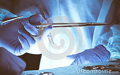 Surgeons hands holding surgical scissors and passing surgical equipment, close-up. Health care and veterinary concept Stock Photo