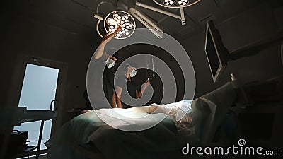 Surgery, medicine and people concept - surgeon in mask adjusting lamp in operating room at hospital. stock footage Surgery, medicine and people concept - surgeon in mask adjusting lamp in operating room at hospital. stock footage