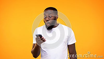 Surprised afro-american guy looking at phone screen, lottery winner, betting app Stock Photo