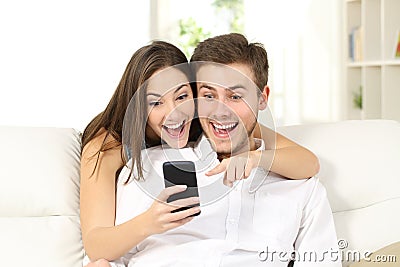 Surprised and amazed couple watching smart phone Stock Photo