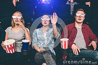 Surprised and amazed people are sitting in chairs in cinema. They are watching movie and looking at the screen with Stock Photo