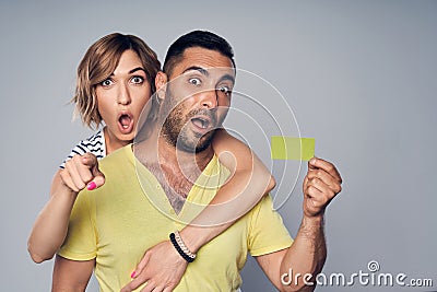 Surprised astonished couple showing blank credit card and pointing at you Stock Photo