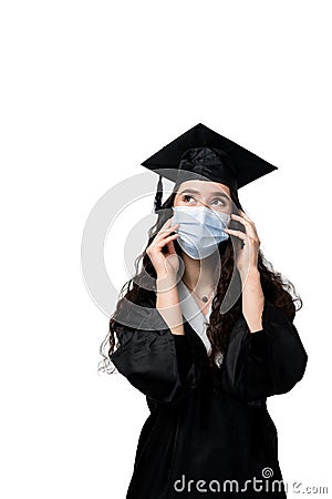 Surprised bachelor girl in medical mask at coronavirus covid-19 period. Master in graduation robe and cap on white Stock Photo