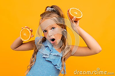 Surprised blond attractive girl with oranges on a yellow background Stock Photo