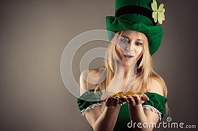 Surprised blond girl in image of leprechaun with gold coins in hands Stock Photo