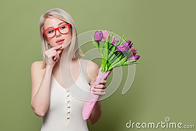 Surprised blonde girl with tulips on green background Stock Photo