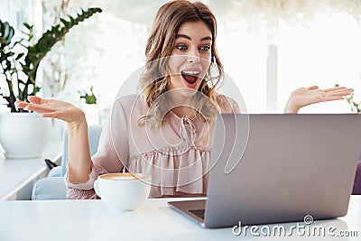 Surprised blondy woman in blouse sitting by the table Stock Photo