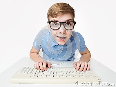 Surprised Child using Computer Keyboard. Teenage Boy Hacker typing on Laptop. Funny Kid In Eye Glasses Study Programming Code Stock Photo