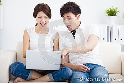 Surprised Couple on sofa with laptop Stock Photo