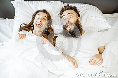 Surprised couple under the bedsheets Stock Photo