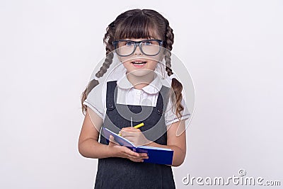 Surprised cute child in eyeglasses writing in notebook using pencil. Five or six years old school kid, on white Stock Photo