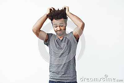 Surprised displeased african man looking down touching hair. White background. Stock Photo
